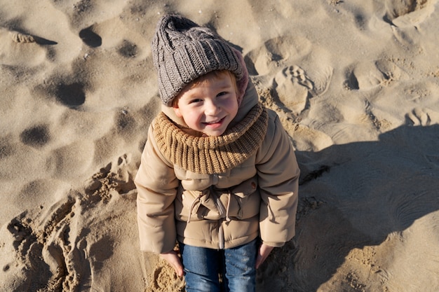 Foto gratuita ragazzo sorridente di alto angolo che si siede sulla spiaggia