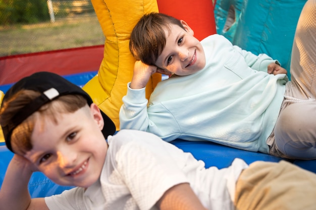 Free photo high angle smiley kids laying in bounce house