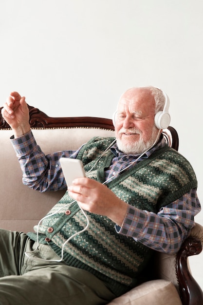 Free photo high angle smiley senior on couch playing music