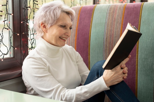 Free photo high angle smiley senior female reading