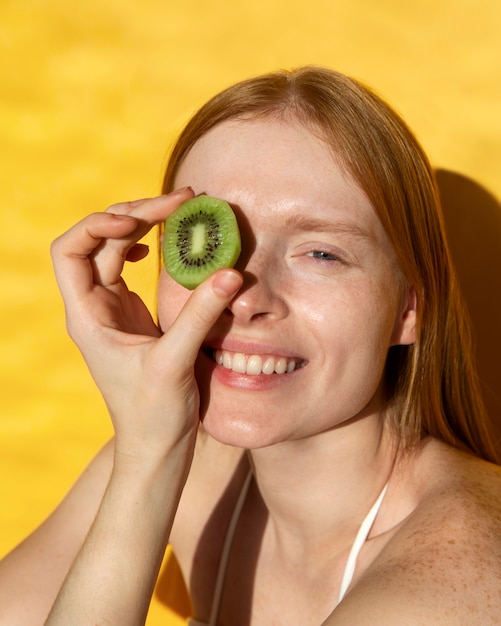 High angle smiley woman holding kiwi