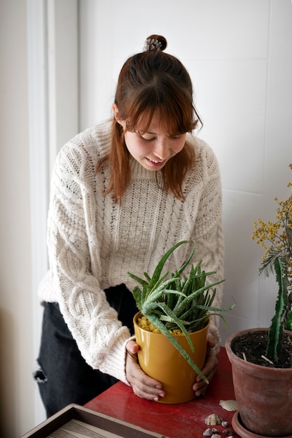 Free photo high angle smiley woman holding plant