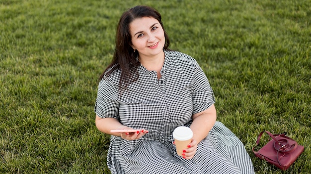 High angle smiley woman sitting on grass