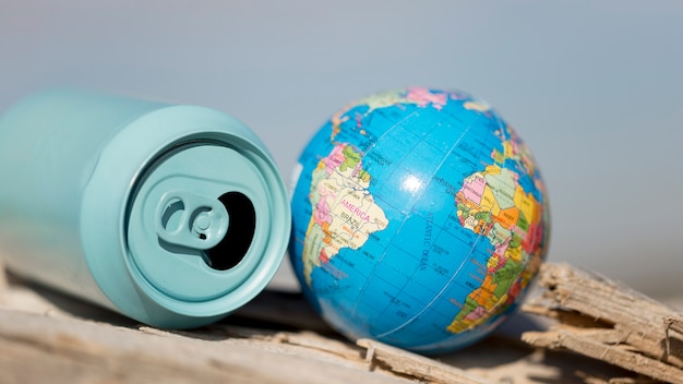 High angle soda can beside small globe