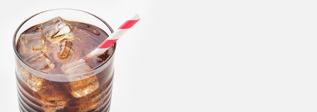 High angle of soft drink in glass with straw and ice cubes