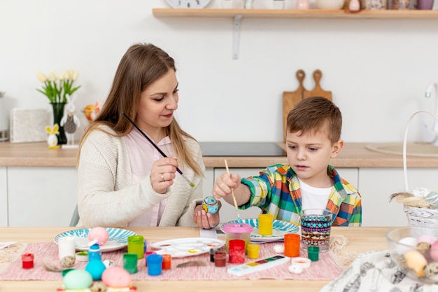 High angle son helping mom to paint eggs