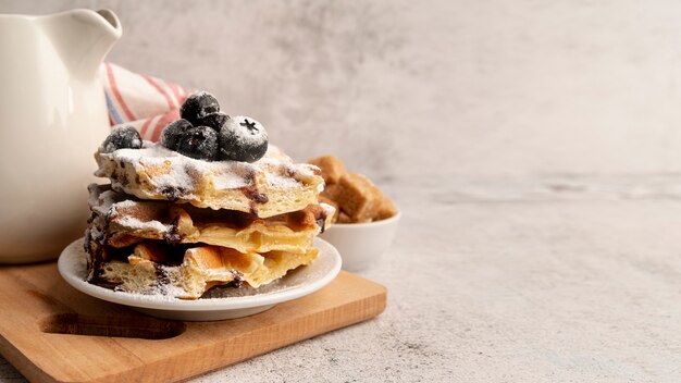 High angle of stacked waffles on plate with powdered sugar and chocolate sauce