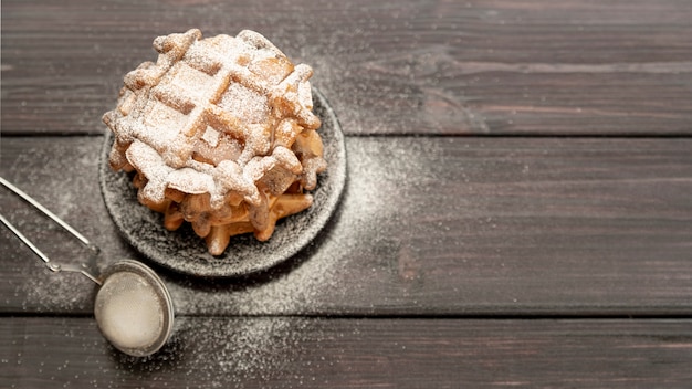 Free photo high angle of stacked waffles on plate with powdered sugar and copy space