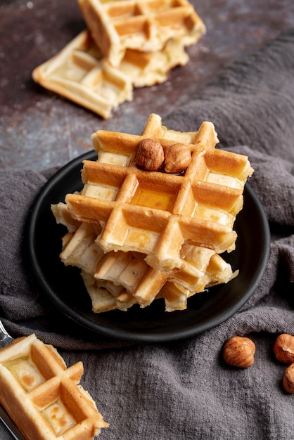 High angle of stacked waffles with hazelnuts and honey