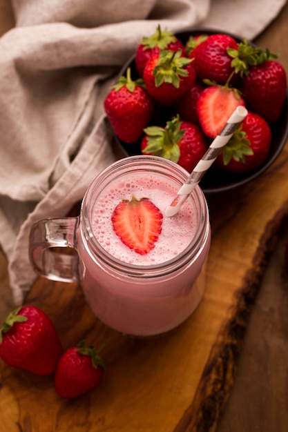 High angle of strawberry milkshake with straw and cloth