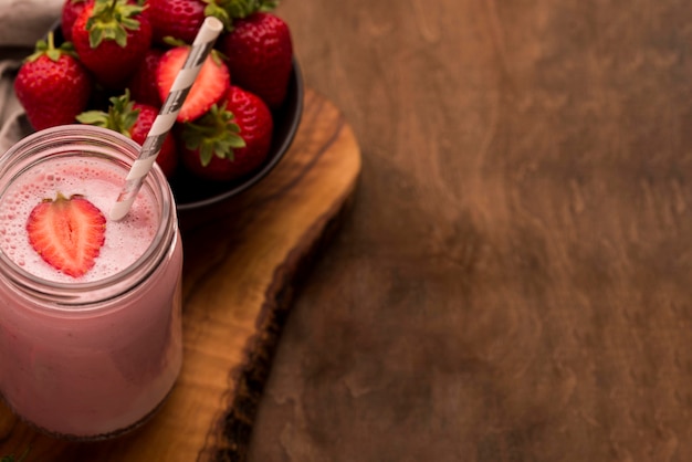 High angle of strawberry milkshake with straw and copy space