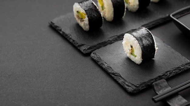 Foto gratuita angolo alto dei rotoli di sushi sull'ardesia con lo spazio della copia