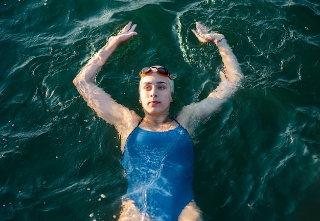 High angle of swimmer with cap and goggles posing while swimming in water