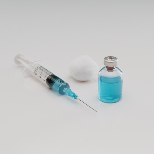 High angle of syringe with cotton and vaccine bottle