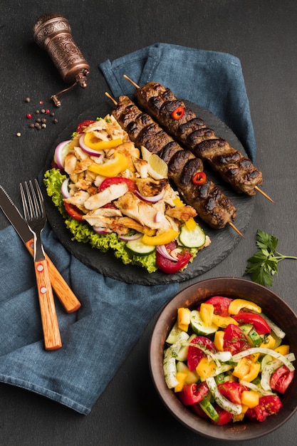 Free photo high angle of tasty kebab on slate with other dish and cutlery