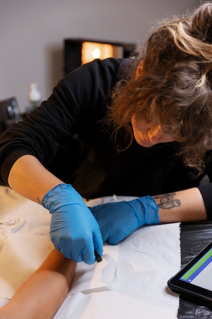 Художник-татуировщик под высоким углом в перчатках