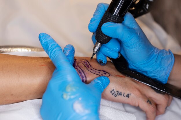 Художник-татуировщик под высоким углом в перчатках