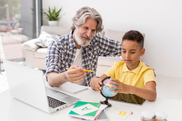 High angle teacher and student looking at earth globe