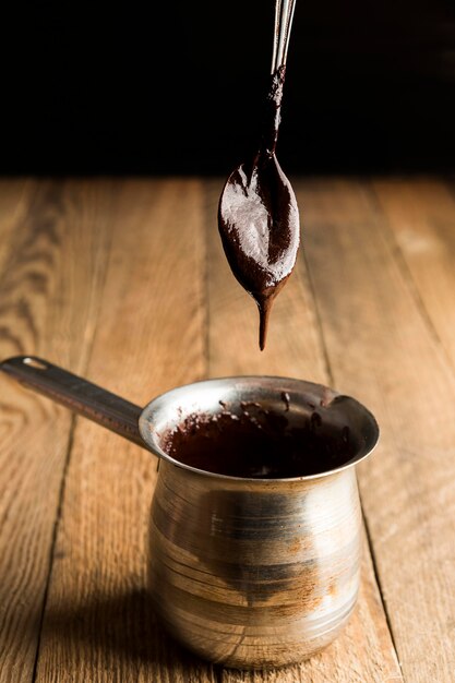 High angle teaspoon with melted chocolate over pot