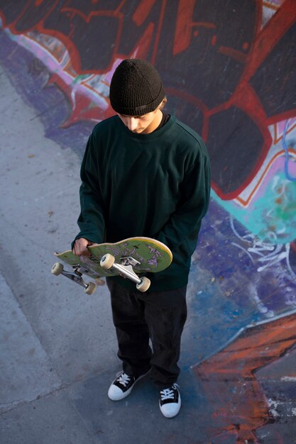 High angle teen holding skateboard outdoors