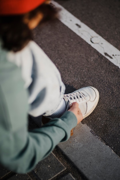 Foto gratuita alto angolo di adolescente che lega i lacci delle scarpe all'aperto