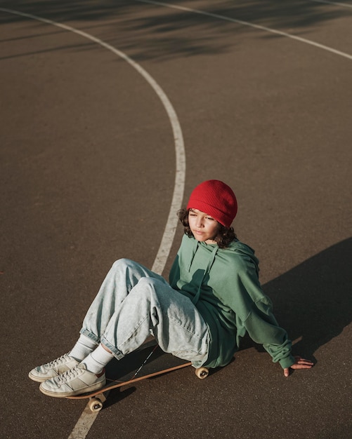 Free photo high angle of teenager with skateboard outdoors and copy space