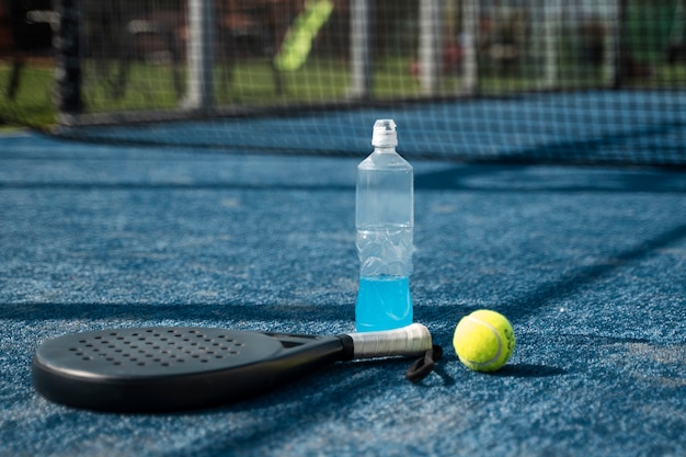 Foto gratuita pagaia da tennis ad alto angolo e bottiglia d'acqua