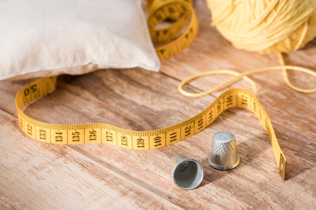 Free photo high angle of thimbles with thread and measuring tape