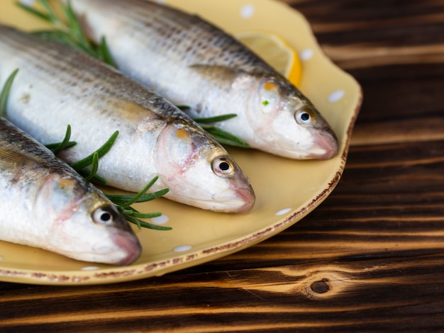 Free photo high angle three fish on plate with herbs