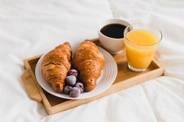 High angle tray with croissants orange juice and coffee