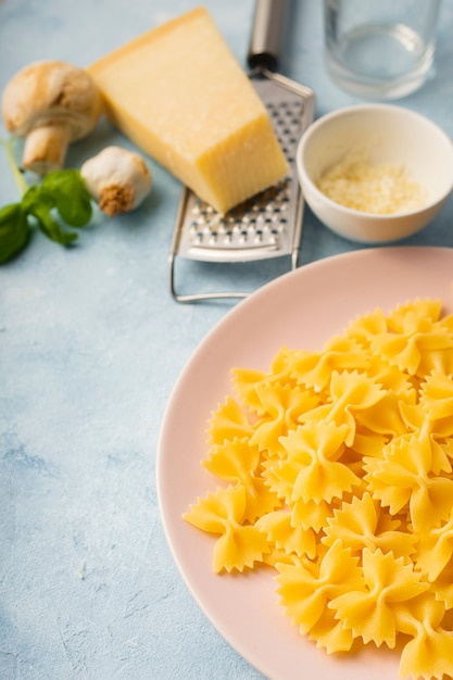 High angle uncooked farfalle in bowl with parmesan