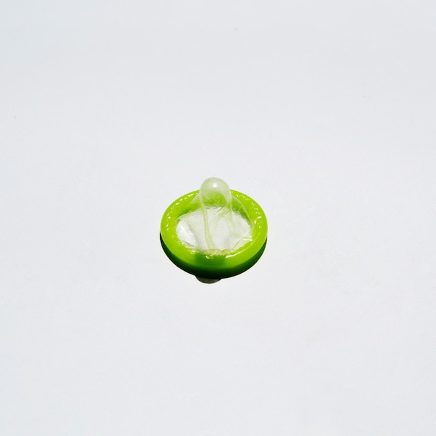 High angle unwrapped condom on white background