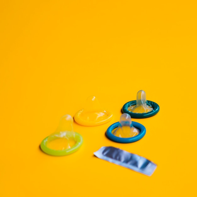 High angle unwrapped condoms on yellow background 