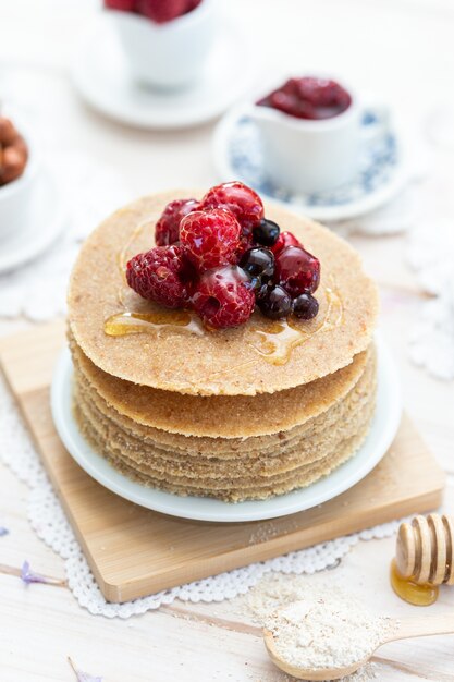 High angle vertical closeup shot of raw vegan pancakes with honey and berries