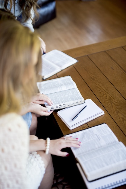 High angle vertical shot of females reading the bible and taking notes