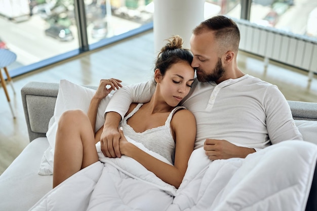 High angle view of affectionate couple lying embraced in the bedroom