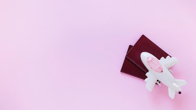 High angle view of airplane and passport on pink surface