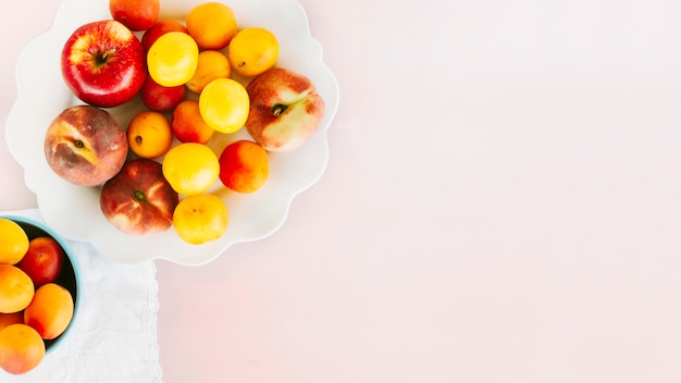 High angle view of apple; peach and plum on pink background