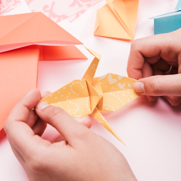 Взгляд высокого угла руки художника держа птицу бумаги origami