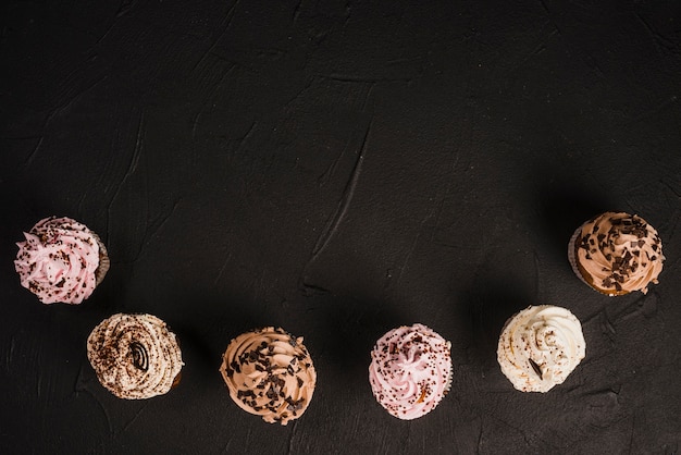 High angle view of assorted fresh tasty muffins on black background