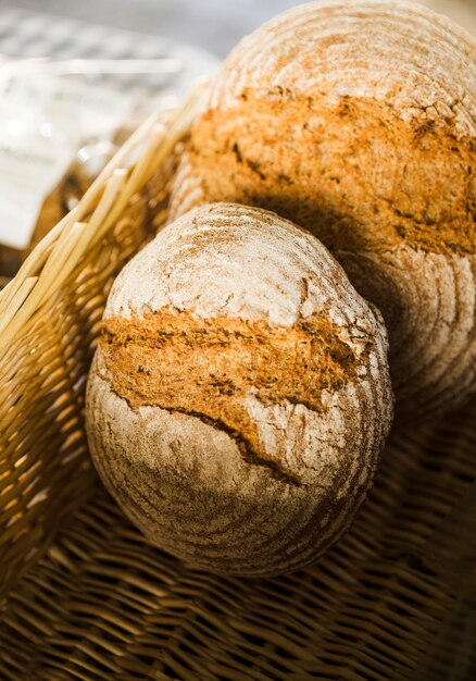 Взгляд высокого угла испеченного хлеба в плетеной корзине на стойле хлебопекарни