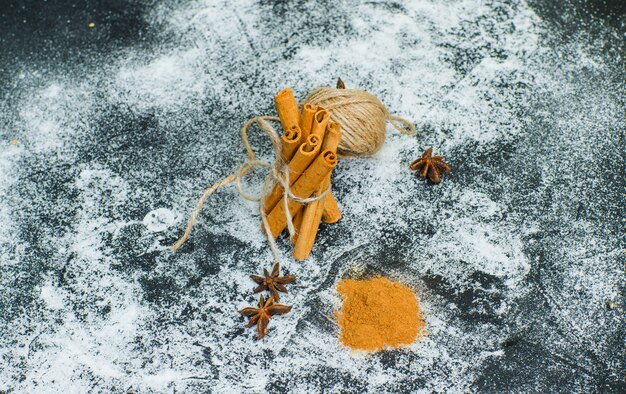 High angle view a ball of rope tied to dry cinnamon with cinnamon powder on gray textured surface. horizontal