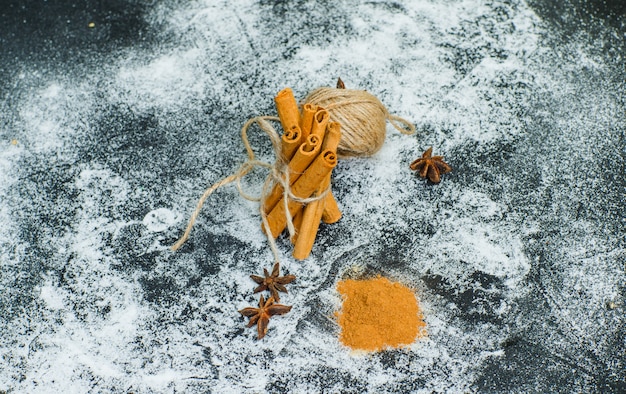 High angle view a ball of rope tied to dry cinnamon with cinnamon powder on gray textured surface. horizontal