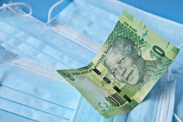 High angle view of a banknote on some surgical masks on a blue surface