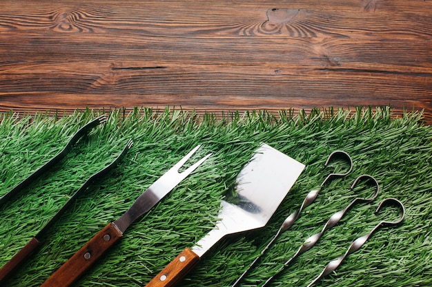 High angle view of barbecue utensil set on green mat over wooden table