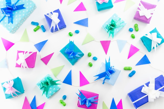 High angle view of birthday gifts and candies son white backdrop