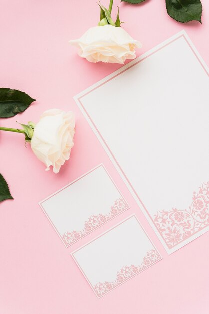 空白のカードとピンクの表面に白いバラの高角度のビュー