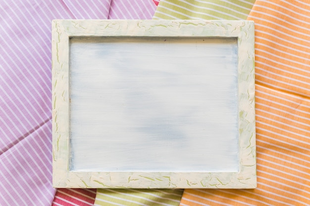 Free photo high angle view of blank picture frame on stripes pattern fabrics