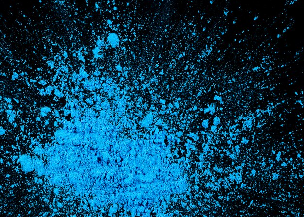 High angle view of blue holi powder on black background