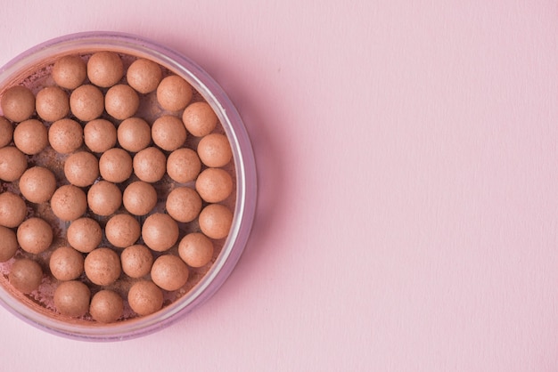 Free photo high angle view of bronzing pearls on pink background